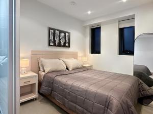 a bedroom with a bed and two windows at CBD Penthouse View Apartment in Adelaide