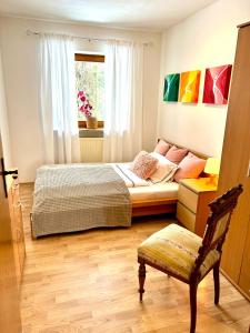 een slaapkamer met een bed, een stoel en een raam bij Privatzimmer Hanna in Dießen am Ammersee
