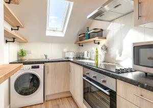 a kitchen with a washing machine and a microwave at 2B Pen Y Bont in Abersoch