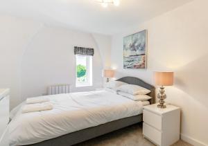 a white bedroom with a bed and a window at 2B Pen Y Bont in Abersoch