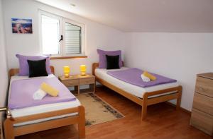 2 bedden in een kamer met paarse lakens en gele kussens bij Villa Renata in Privlaka