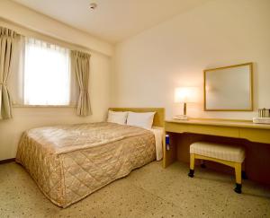 倉敷市にある倉敷駅前ユニバーサルホテルのベッドとデスクが備わるホテルルームです。