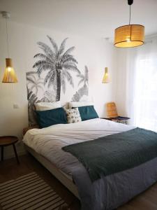 1 dormitorio con 1 cama grande con palmeras en la pared en Hébergement Penmarch 800 m plage, 10 mn La Torche, en Penmarch