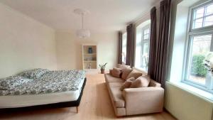 ein Schlafzimmer mit einem Bett, einem Sofa und Fenstern in der Unterkunft Apartment in Danmark -Petersminde Exclusive Apartments in Otterup
