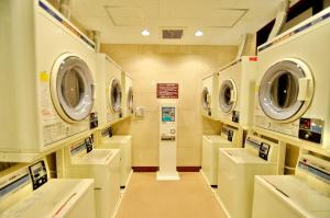 een wasruimte met meerdere wasmachines en wasmachines bij Okayama Ekimae Universal Hotel in Okayama