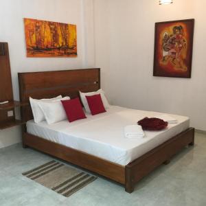 uma cama com almofadas vermelhas e brancas num quarto em Moon Deck Villa em Katunayaka