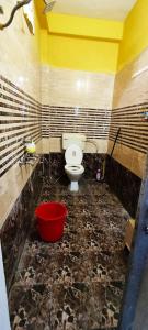 een badkamer met een toilet en een rode emmer bij Ramashray - Spiritual कुटिया in Ayodhya