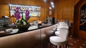 a bar with white chairs and a counter with purple flowers at Hotel Lechnerhof Unterföhring in Munich