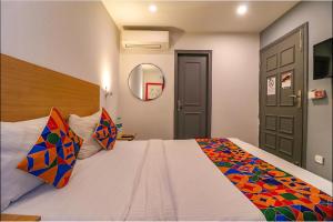 1 dormitorio con 1 cama blanca grande con almohadas coloridas en FabHotel La Serene Punjabi Bagh en Nueva Delhi