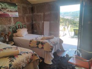 - une chambre avec 2 lits et une porte coulissante en verre dans l'établissement A casa do Pastorinho, à Baião