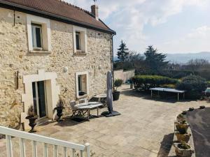 une terrasse en face d'une maison en pierre avec un banc dans l'établissement Domaine de famille Dovie, à Château-Thierry