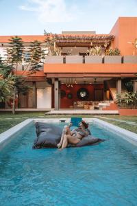 two people laying on a bed in a swimming pool at Lasai Villas in Gili Air
