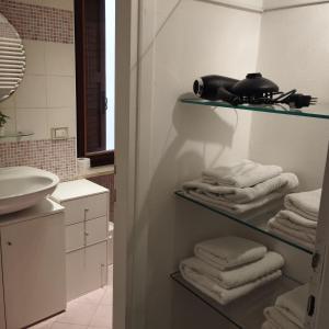 uma casa de banho com uma prateleira com toalhas e um lavatório em AL VICOLETTO em Verona