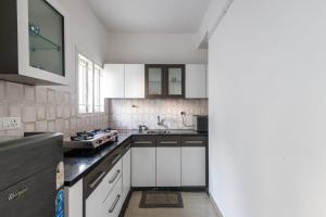 eine Küche mit weißen Schränken und einem Herd in der Unterkunft Downtown Apartment by JadeCaps AC 2BHK Near CBD in Bangalore