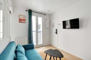 a living room with a blue couch and a tv at Modern and functional apartment Ménilmontant in Paris