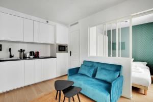 a living room with a blue couch and a kitchen at Modern and functional apartment Ménilmontant in Paris