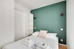 a bedroom with a white bed with a green wall at Modern and functional apartment Ménilmontant in Paris