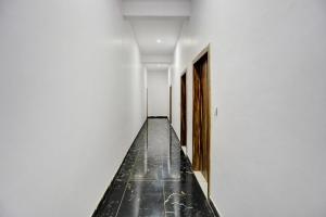 a hallway with white walls and a black floor at OYO Flagship Sardarji Hotel And Restaurant in Bāzpur