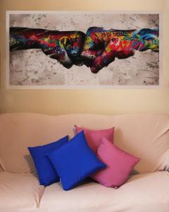 a painting of a hand is above a couch with pillows at Casa Elvira in Nonantola +2 photos