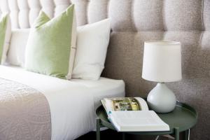 a bed with a table with a book and a lamp at The Apollo in Apollo Bay