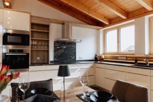 cocina con techo de madera y mesa con sillas en Alpen Apart Allgäu, en Oy-Mittelberg