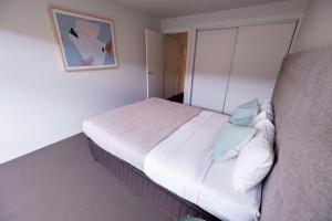 a bedroom with a bed with white sheets and blue pillows at The Apollo in Apollo Bay