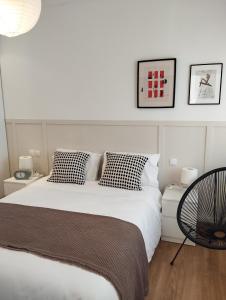 - une chambre avec un grand lit blanc et une chaise dans l'établissement Casa Golf49 con parking, à Badajoz