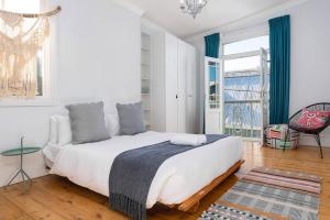 a white bedroom with a large bed and a window at Victorian Townhouse with Table Mountain Views in Cape Town +21 photos