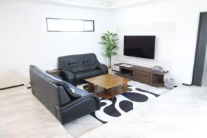 uma sala de estar com duas cadeiras e uma televisão em Condominium Felicita Naha em Naha