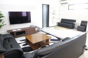 uma sala de estar com um sofá e uma televisão em Condominium Felicita Naha em Naha