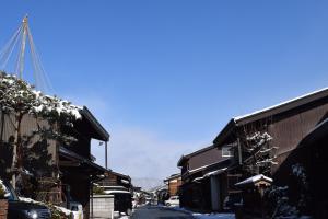a snow covered street in a town with buildings at Karin House in Takayama