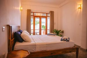 1 dormitorio con 1 cama grande y ventana en Abhaya Villas, en Madihe East