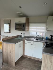 a kitchen with white cabinets and a counter top at GDs Luxury Caravan Hire Turnberry Holiday Park in Turnberry