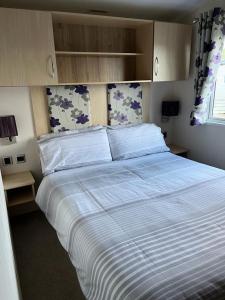 a bedroom with a large bed with white sheets at GDs Luxury Caravan Hire Turnberry Holiday Park in Turnberry
