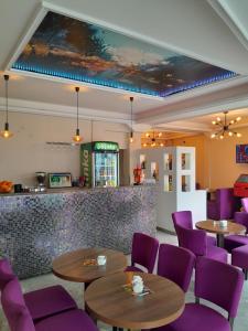a restaurant with purple chairs and tables and a counter at Hotel PEKING in Sarajevo