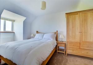 1 dormitorio con 1 cama blanca grande y armario de madera en Lucerne en Saint Ervan