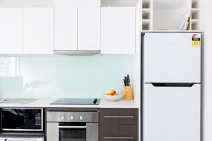 a kitchen with white cabinets and a refrigerator at The Apollo in Apollo Bay