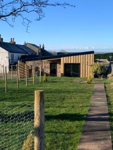 a house in a field with a fence at The CowShed Cottage - Beautiful Location in Lancaster
