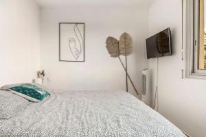 - une chambre blanche avec un lit et une télévision dans l'établissement Appart avec piscine, entre plage, port et falaises, au Cap d'Agde