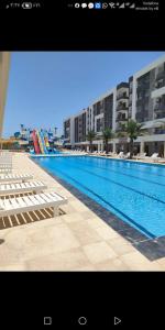 a large swimming pool with white chairs and buildings at فنادير in Hurghada
