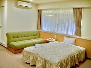 Matsue Universal Hotel في ماتسو: غرفة نوم بسرير واريكة ونافذة