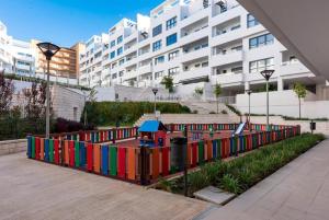 une clôture colorée avec une aire de jeux en face d'un bâtiment dans l'établissement Estepona terrace & pool Apartment, à Estepona