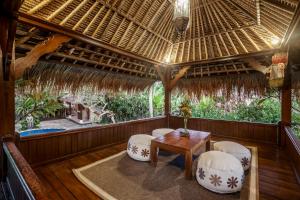 porche con sillas, mesa y techo de paja en Villa Sujati en Ubud
