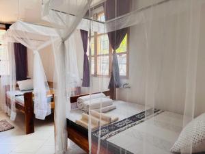 a bedroom with a canopy bed with a window at Karibu Africa Home in Moshi