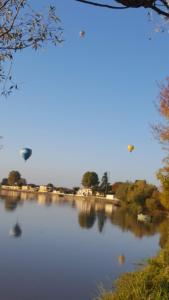 een heteluchtballon die over een rivier vliegt bij Maison au Coin, proche St Emilion in Sainte-Terre