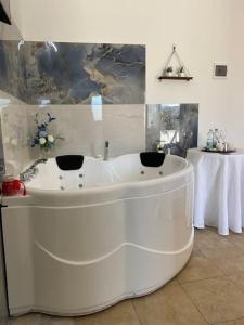 a large white bath tub in a room with a table at B&B Suite "Caniglia" in Mesagne