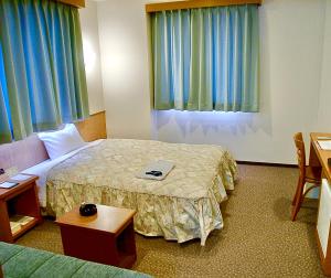 米子市Yonago Universal Hotel的一间带床和桌子的酒店房间