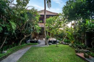 un jardín frente a una casa con árboles en Villa Sujati en Ubud