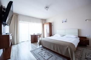 a bedroom with a large bed and a large window at Pensiunea Andy in Braşov