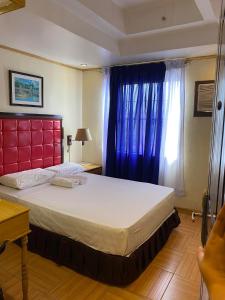 a bedroom with a large bed with a red headboard and a window at Sugarland Suites in Ormoc +8 photos